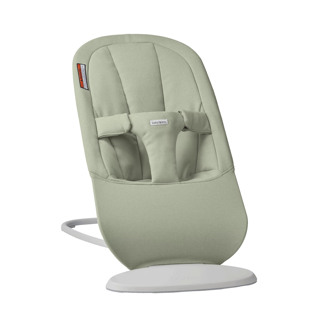 Olive-green baby bouncer with padded seat, safety harness, and a sturdy white base.